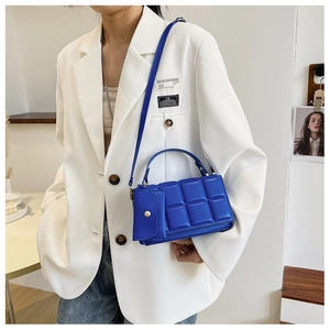 Detail of dark blue quilted crossbody bag with matching detachable pouch and slim strap