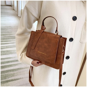 Gros plan d'un petit sac bandoulière marron en cuir texturé avec détails dorés et anse