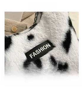 Détail du sac cabas en peluche imprimé vache avec étiquette FASHION et bandoulière chaîne