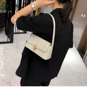 Detail of cream crocodile embossed underarm bag with gold twist lock on shoulder