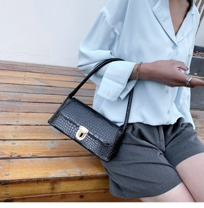 Detail of black crocodile pattern baguette bag featuring elegant gold metal square buckle