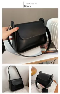 Detail shot of matte black rectangular crossbody bag with gold-tone metal hardware