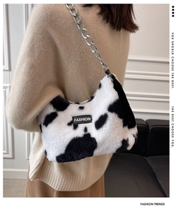 Détail du sac bandoulière en peluche à motif vache avec chaîne argentée et logo