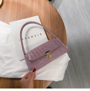 Detail of light purple crocodile pattern baguette bag with a gold metal buckle