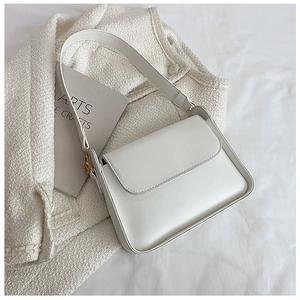 Detail of white leather shoulder bag with gold hardware on tweed background