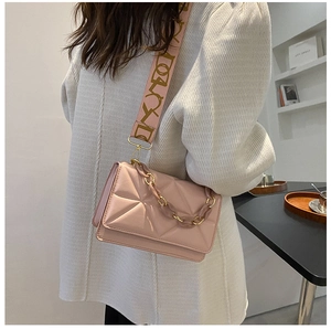 Pink quilted crossbody bag with wide shoulder strap and chunky chain detail shown on model