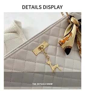 Detail of light gray quilted handbag featuring gold elk charm and silk scarf handle decor
