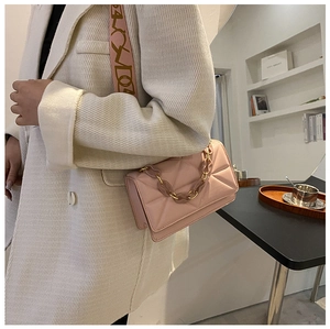 Detail of pink quilted crossbody bag with decorative chain strap and printed shoulder strap