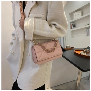 Detail of pink crossbody bag with geometric quilting and golden chain handle