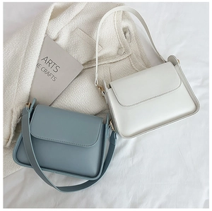 Detail of minimalist leather crossbody bags in pearl white and grey-blue with gold buckles