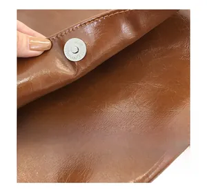 Detail of metal magnetic clasp on brown lychee pattern leather shoulder bag