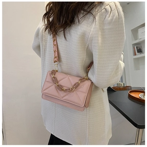 Detailed shot of pink quilted crossbody bag with decorative chain and wide patterned strap