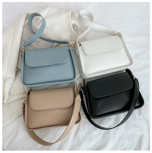 Flat lay of vintage style flap bags in four colors with wide straps on white fabric