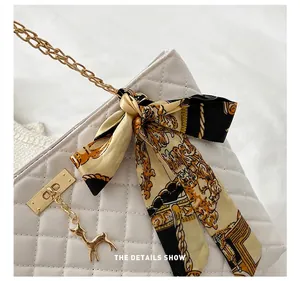 Detailed macro view of white quilted shoulder bag with gold chain and printed silk scarf