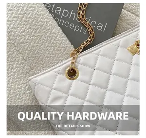 Close-up of golden metal rings and chain detail on white quilted crossbody bag