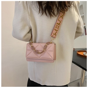 Detailed close-up of pink geometric quilted handbag with chain and jacquard strap