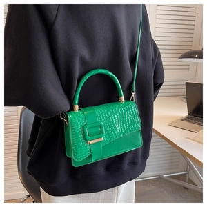 Detail of green crocodile embossed texture bag with large square buckle and gold hardware