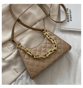 Dettaglio borsa trapuntata kaki con catena dorata e tracolla su blazer beige chiaro
