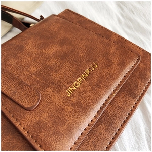 Gros plan sur sac en cuir marron vintage avec logo doré et finitions cousues main