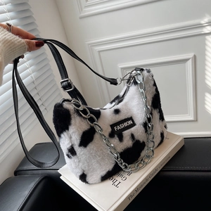 Détail du sac en peluche imprimé vache avec chaîne argentée et étiquette FASHION