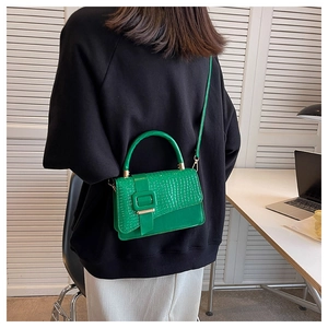 Detail of lime green faux crocodile leather handbag with metal buckle and shoulder strap