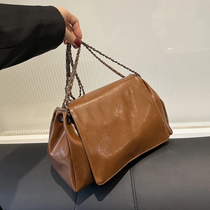 Détail du sac à bandoulière en cuir marron brillant avec chaîne en métal vintage