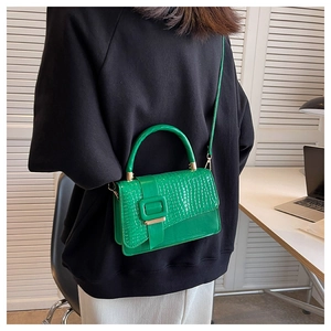 Detail der hellgrünen Handtasche mit Krokodilmuster und Umhängeriemen am Modell