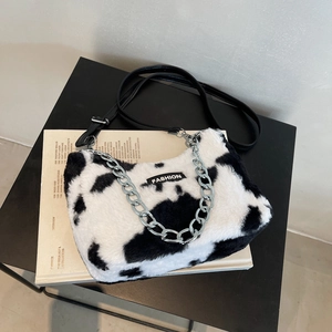 Détail du sac pelucheux à motif vache avec chaîne argentée et étiquette de mode