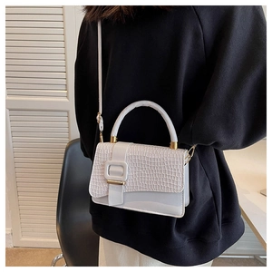 Detail showing white crocodile embossed leather texture on a stylish square handbag
