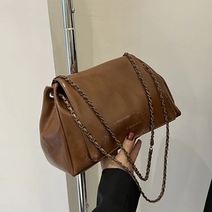 Détail de la bandoulière chaîne en cuir marron foncé avec texture froissée brillante