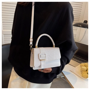 Detail of white crocodile texture bag with large decorative square buckle and gold hardware