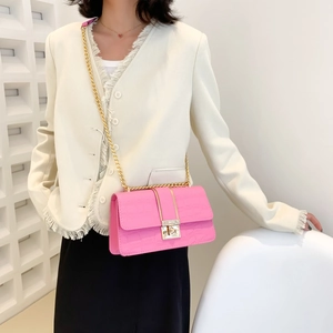 Pink crocodile pattern shoulder bag with gold clasp and chain strap on a model