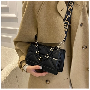Detail of black quilted shoulder bag featuring gold chain and patterned wide fabric strap