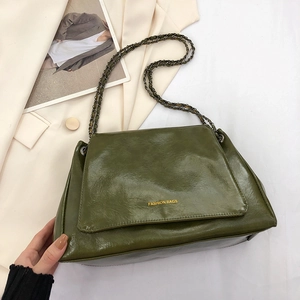 Détail du sac à main en cuir ciré vert foncé avec logo doré et bandoulière chaîne