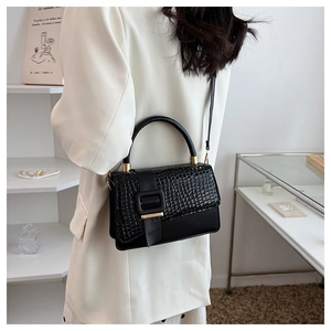Detail of black crocodile texture handbag with gold hardware and smooth leather stitching