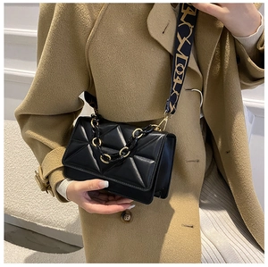 Detail of black quilted shoulder bag with gold chain handle and wide patterned strap