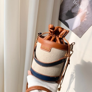 Dettaglio borsa a secchiello in tela con patchwork in pelle, coulisse e manico di perle