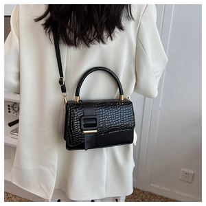 Model wearing a black crocodile-embossed leather handbag with gold metal hardware