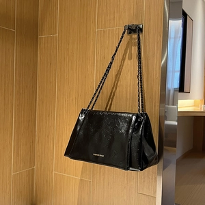Détail d'un sac à bandoulière en cuir verni noir brillant avec bandoulière chaîne