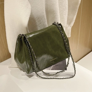 Gros plan détaillé d'un sac en cuir vert foncé brillant avec chaîne en métal noir
