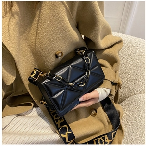 Detail of black geometric embossed leather bag with gold-tone chain and wide strap