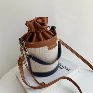 Dettaglio borsa a secchiello in tela bicolore con coulisse in pelle e manico di perle