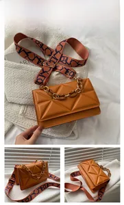 Detail of brown quilted crossbody bag with amber resin chain and graphic strap