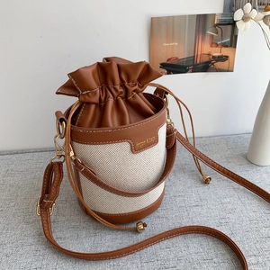 Dettaglio della borsa a secchiello in tela con coulisse in pelle e tracolla regolabile