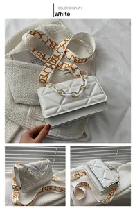 Detail view of white quilted crossbody bag featuring chic orange patterned wide strap