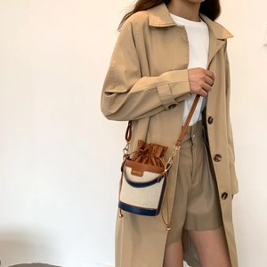 Dettaglio borsa a secchiello in tela crema con finiture in pelle marrone e coulisse