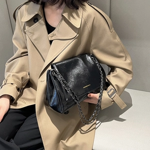 Mannequin portant un sac bandoulière noir en cuir huilé avec un trench-coat classique