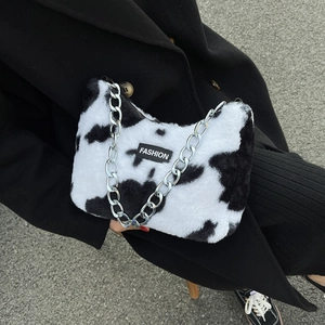Détail du sac cabas en peluche imprimé vache avec étiquette noire et bandoulière chaîne