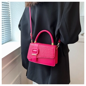 Detail of rose red crossbody bag featuring crocodile texture flap and metal buckle
