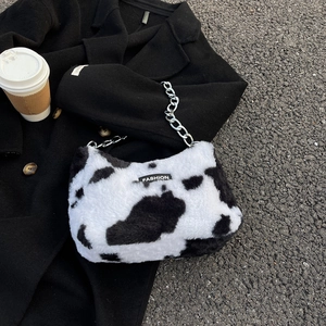 Détail du sac cabas en peluche motif vache avec chaîne argentée et étiquette mode